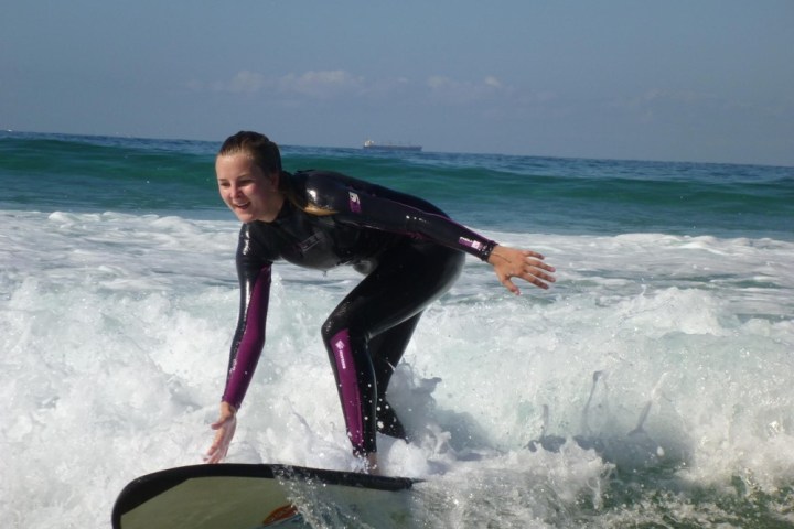 a young girl riding a wave on a surfboard in the ocean