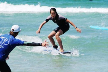 Teenage girl doing surfing lesson with the trainer