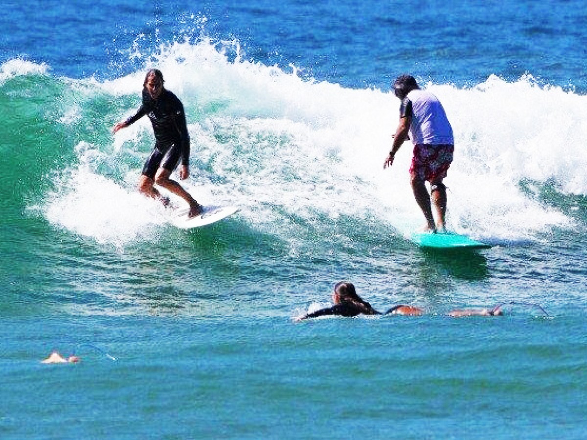 4 teens doing surfing lessons on the beach