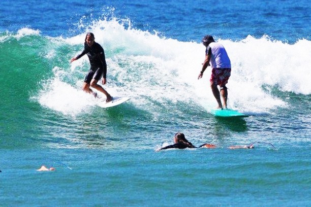 4 teens doing surfing lessons on the beach