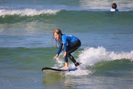 a small girl riding a wave on a surfboard in the water